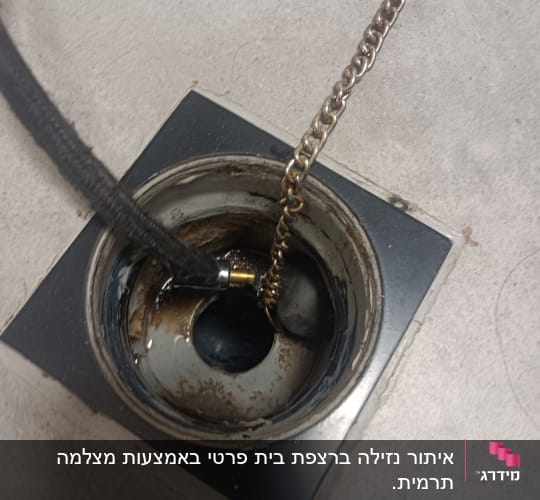 צינור ושרשרת בתוך פתח ניקוז מלוכלך